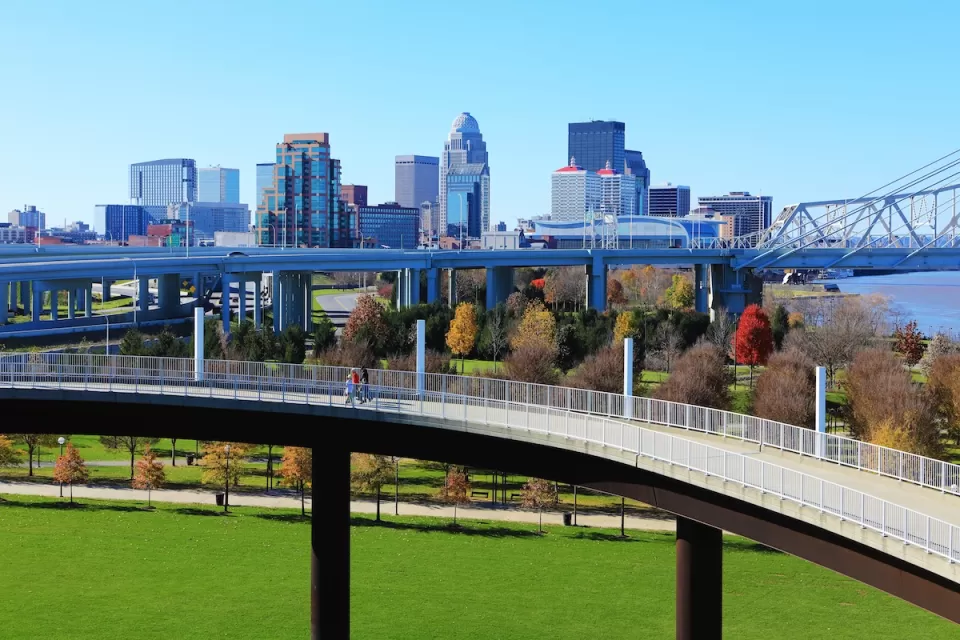 Skyline of Louisville, Kentucky with pedestrian walkway in foreground and vehicle bridge.